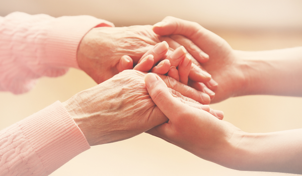 elderly hands clasping young woman's hands.