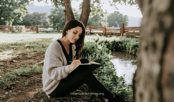 Woman relaxing on a couch with a book in her lap and holding a cup of tea, practicing self-care and prioritizing her mental health.