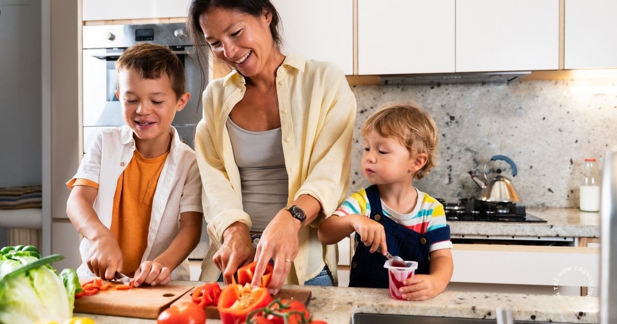 Mom cooking dinner while managing two kids in a busy kitchen, showing the mental load of motherhood