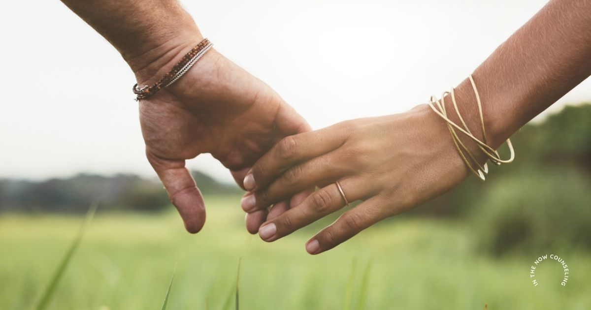 Woman and partner’s / husbands hands reaching but not touching, symbolizing emotional distance in a relationship and the desire to reconnect with her partner