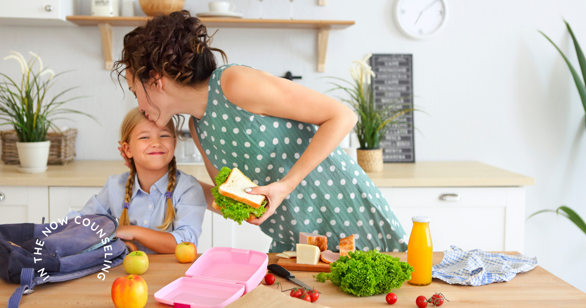 mom kisses her daughter while packing her lunch and back to school bag showing the stress for moms for school